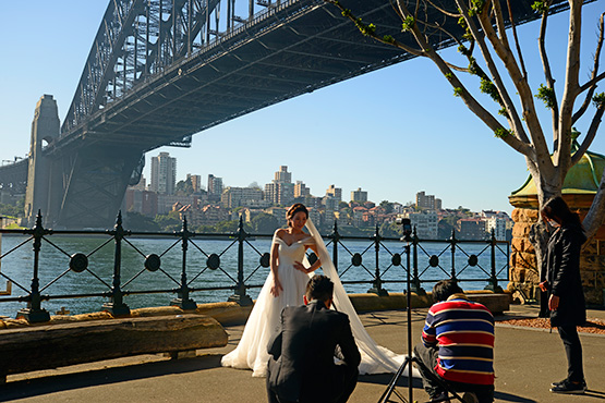 A bride gets her wedding photos taken under the Sydney Harbour Bridge at Dawes Point